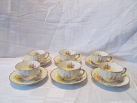 Six Sovereign Potters floral teacups and saucers displayed together on a white cloth background.