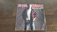 Front of Summer Of '69 Bryan Adams 45rpm vinyl single sleeve, showing Bryan Adams in checkered shirt, jeans, and white t-shirt.