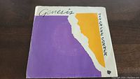 Front side of Genesis Man On The Corner 45rpm vinyl single sleeve, featuring purple, white and orange abstract artwork with Genesis and track title.