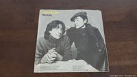 John Lennon Woman 45 RPM vinyl single sleeve with black and white photo of John Lennon and Yoko Ono, slight wear visible on sleeve.