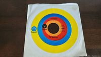 Photo of The Beatles 'Yesterday' 45rpm vinyl single with original Capitol sleeve, colorful label with yellow and blue rings.