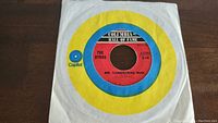 Front view of one 45rpm vinyl record showing the Columbia Hall of Fame center label and Capitol paper sleeve with yellow and blue target design.