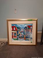 Full front view of framed painting showing village street scene and children playing hockey