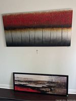 Wall display showing two art pieces: top textured canvas painting of trees with red, black, and gray colors, bottom framed abstract print with red and earth tones