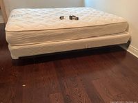 Full side view of the bed frame holding mattress and box spring, showing the frame structure and wheels.