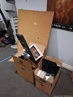 Cork bulletin board standing upright behind two boxes of frames and albums