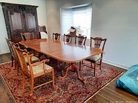 Full set of eight wooden chairs around a dining table in a room with a patterned rug, showing both captain and side chairs.
