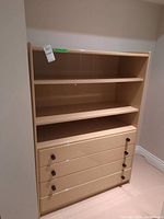 Front view of wood dresser showing two open shelves on top and four drawers below, drawer knobs visible but one handle is missing.