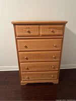 Front view of five drawer wood dresser showing two smaller top drawers and three larger drawers below with round wooden knobs.