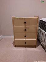 Front view of beige wood end table showing four drawers with round black knobs