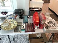 Overview of various kitchen ware items on a table including boxed cutlery, serving trays, and wine accessories