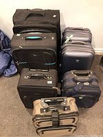 Full set of seven luggage pieces arranged on the floor, showing a variety of soft and hard-sided cases in black, tan, and gray colors.