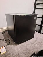 Front and right side view of the Kenmore mini fridge showing black exterior and logo on door