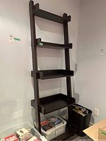 Front view of the wooden ladder-style shelf showing all five fixed shelves with tray edges and dark finish.
