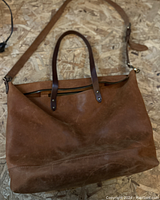 Full view of Krux Garage leather handbag showing light brown distressed leather, two short handles, and a detachable shoulder strap.