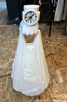 Full view of white LED light-up sculpture in shape of hand holding a shopping bag with integrated clock at wrist.