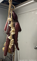 Hanging plastic display including meat-like sausages and garlic bulbs for window arrangement.