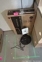 Photo showing LG 22-inch LED monitor box and a circular black monitor stand with cables.