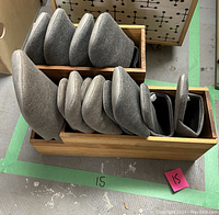 Seven pairs of gray indoor slippers arranged in a wooden storage box with three compartments, visible in a top-down photo.