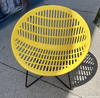 Top-down view of a single yellow plastic bowl seat and black iron X-frame