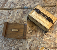 Two handmade wooden boxes laying on a wooden textured surface with a folding ruler for size reference.