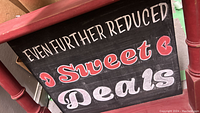 Close-up photo of chalkboard with handwritten chalk text 'Even Further Reduced Sweet Deals' in white and red chalk.