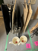 Photo showing five clipboards, two white ceramic mugs, and vintage black rack hung on metal rods.