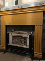 Photo of the yellow painted vintage fireplace mantle showing its front and side details with floral carvings.