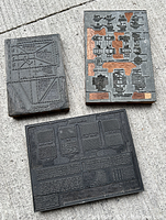 Three vintage industrial printer's blanks placed outdoors on concrete surface in daylight.