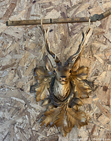 Front view of the vintage plastic deer head mount showing detailed antlers and oak leaf background, with measuring stick above for scale.