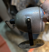 Side view showing the textured silver-gray metal spotlight lamp with its adjustable black arm and circular base.