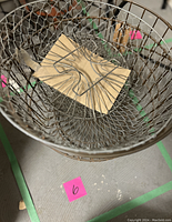 Top view of the vintage wire basket showing its wire mesh interior and a cardboard piece on the bottom.