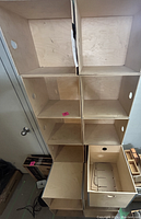 Overhead view showing 13 wooden stacking boxes, arranged in a grid pattern. Each box is a cube with circular finger holes on the sides for handling. Light wood finish with natural grain visible.