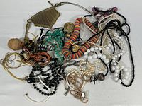 Top-down view of assorted necklaces and bracelets in a pile showing various beads, chains, and pendants.
