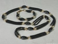 Full view of the polished stone necklace and matching bracelet laid out showing length and bead detail.