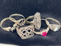 Full view of six silver rings showing various designs and sizes.