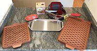 Two Copper Chef pans with grid surfaces on top, stainless steel All-Clad pan, ceramic blowfish butter warmer in box, and coral Fiesta butter dish lid visible