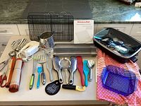 Full top-down view of all items including Presto electric skillet, cooling racks, KitchenAid mixer, various utensils, baking mats, vegetable peeler, and glass baking dish.