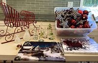 Overview of the Christmas decor items on table including canvas art, decorative sleigh, glass trees, ornaments