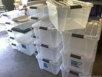 Overall view of 15 clear plastic storage totes in multiple stacks