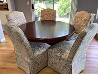 Top down view showing round table surface and five paisley upholstered chairs around it.