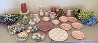 Group of Easter and pink polka dot themed dishes, candles, bunny figurines, floral arrangements and decorative eggs displayed on a table