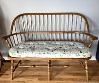 Full front view of the Ethan Allen wooden bench with spindle back and floral cushion on wooden floor.