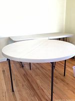 Photo showing round and rectangular Lifetime folding tables from side angle, both open and standing on wooden floor.