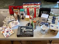 Overview of the lot showing kitchen gadgets, storage bags, textiles, and boxed items arranged on a table.