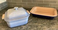 Two Le Creuset baking dishes side by side on counter, one with lid on, one without lid revealing interior