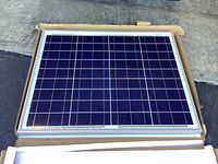 Front view of the new Renogy 50W 12V monocrystalline solar panel in original box showing the solar cells and aluminum frame.