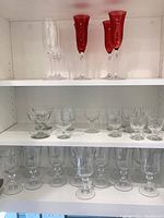 Closer view of the clear and red crystal champagne flutes on top shelf