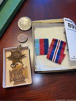 Photo showing all items in the lot including two medals, two coins, and a box with ribbons.