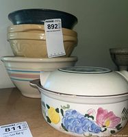 Five ceramic bowls stacked, four mixing bowls and one casserole dish with floral and fruit design with chip